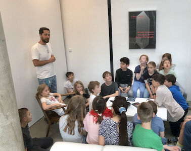 Die Kinder hören bei der Führung durchs Kunsthaus genau zu. Ein Mann erzählt ihnen spannende Fakten über dieses Gebäude.