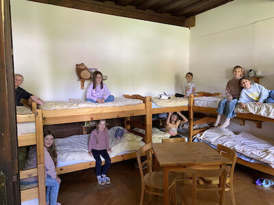 Sieben Kinder sitzen auf Etagenbetten in einem gemütlichen Schlafzimmer mit Holzmöbeln.