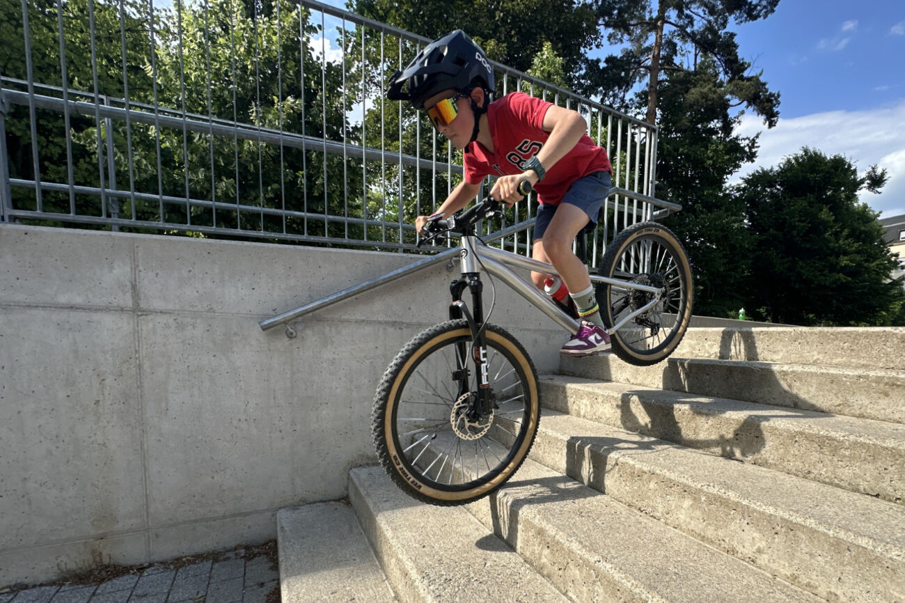 Ein Bub fährt mit dem Mountainbike eine kurze Stiege hinunter.