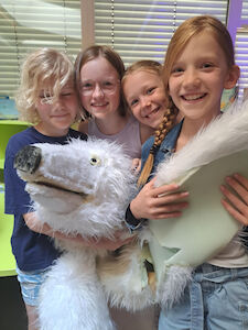 Vier Kinder mit einer großen Theaterpuppe.