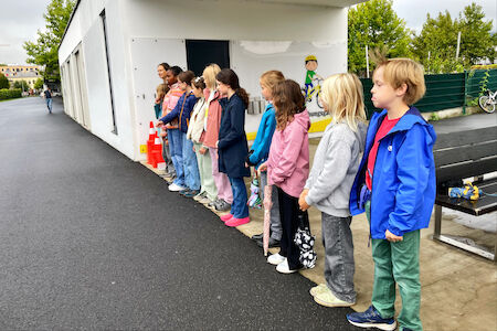 Es sind Kinder zu sehen, die am Rand stehen und das Geschehen mit dem Auto und dem Bremsweg aus sicherer Entfernung beobachten.