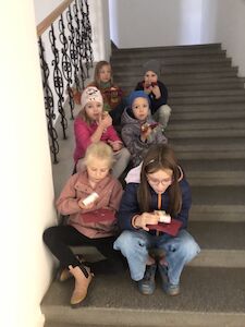 Auf der Stiege sitzen sechs Kinder paarweise hintereinander.