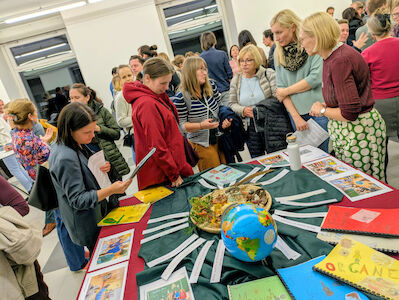 Viele interessierte Eltern stehen um den dekorierten Tisch vom "Jenaplan-Team" und kommen mit den Lehrerinnen ins Gespräch.