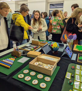 Viele interessierte Eltern stehen um den dekorierten Tisch vom "Montessori-Team" und kommen mit den Lehrerinnen ins Gespräch.