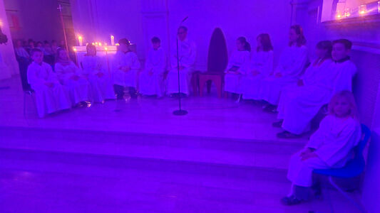 Blick auf den Altarraum, wo viele Ministrant*innen sitzen.