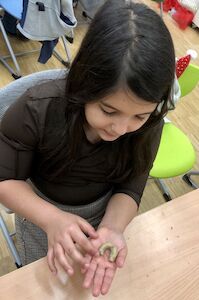 Ein Mädchen mit dunklen Haaren formt ein Vanillekipferl.