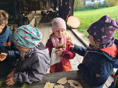 Ein Holzpuzzle wird von Kindern näher betrachtet.