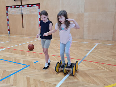 Ein Mädchen hilft einem anderen Mädchen beim Pedalo-Fahren.