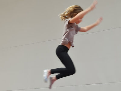 Ein Mädchen im Sprung mit erhobenen Armen.