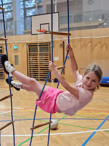 In einer der Hängeleitern sitzt gemütlich ein Mädchen und lacht.