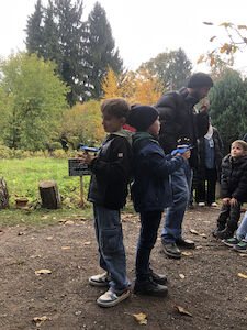 Zwei Kinder stehen Rücken an Rücken und halten dabei etwas in Händen.