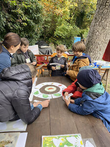 An einem Tisch wird ein Kreis-Puzzle über den Schmetterling gelegt und darüber diskutiert.