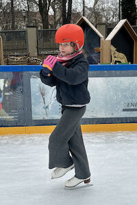 Ein Mädchen macht eine Pirouette mit den Eislaufschuhen am Eis.
