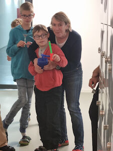 Ein Bub wird beim Flug-Contest von einer Schulassistentin unterstützt.