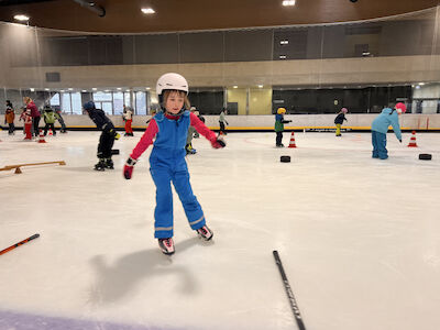 Ein Kind fährt in Kurven durch einen Hindernisparcours übers Eis.