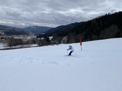 Ein Kind fährt gerade die Rennpiste den Berg hinunter.