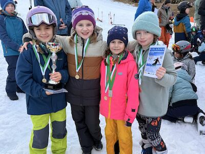 Vier Kinder posieren stolz mit ihren Medaillen und Urkunden.