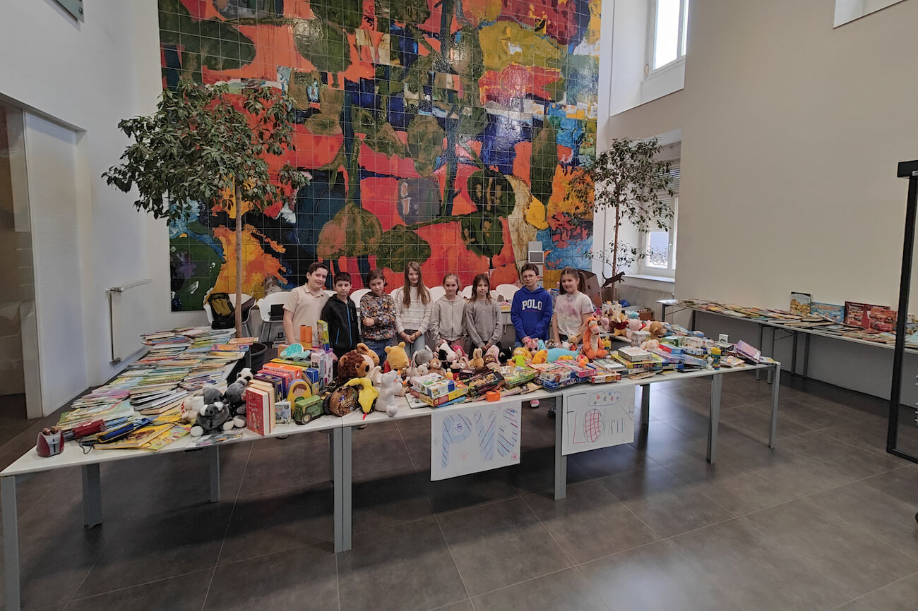 Die Schulrätin*innen kurz vor dem Flohmarkt-Verkaufbeginn hinter den Tischen mit vielen Spielen, Kuscheltieren etc.