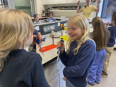 Mehrere Kinder hantieren mit Laborwerkzeugen und haben ihre Freude dabei.