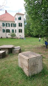 Außenansicht des Schlosses, wo Kinder miteinander auf der Wiese spielen.