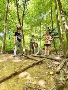 Vier Kinder haben ihren Spaß beim Ausprobieren ihrer selbstgebauten Waldkugelbahn.