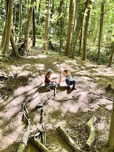 Zwei Kinder arbeiten fleißig an einer Kugelbahn im Wald.