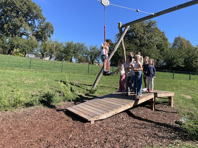 Eine Kindergruppe steht bei der Seilrutsche und schiebt einem Kind an.