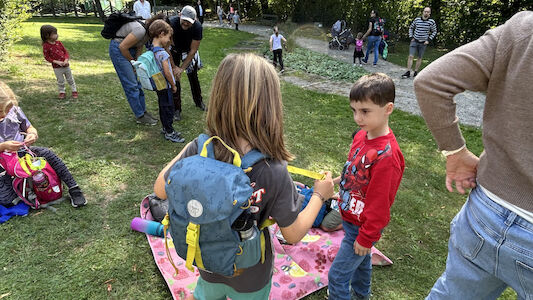 Kinder stehen bei einer Picknickdecke und unterhalten sich.