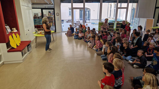 Eine Lehrerin spricht bei der Erntedankfeier zu den Kindern im Begegnungsraum.