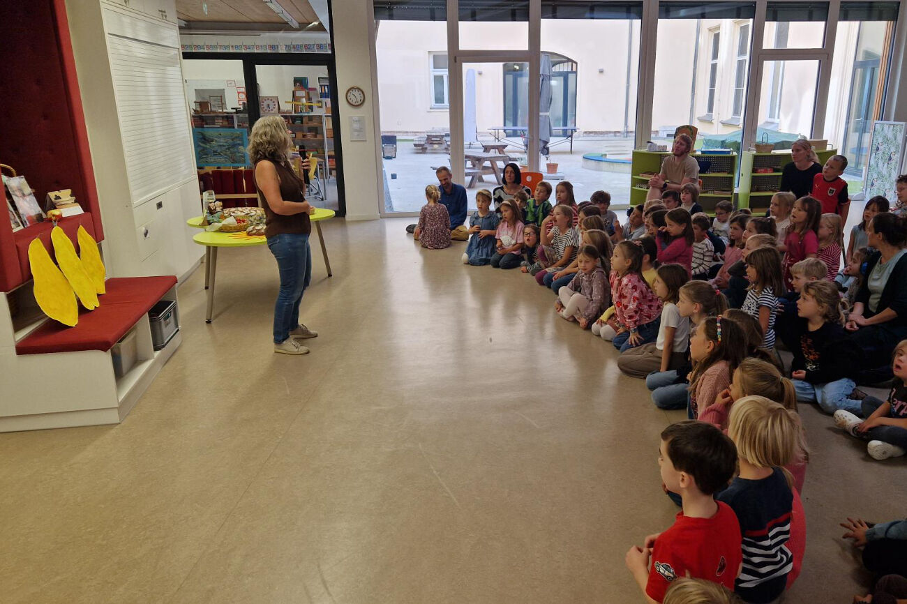 Eine Lehrerin spricht bei der Erntedankfeier zu den Kindern im Begegnungsraum.